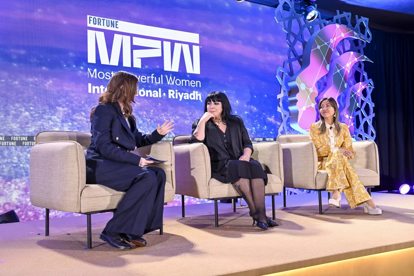 three women in panel discussion on stage at conference