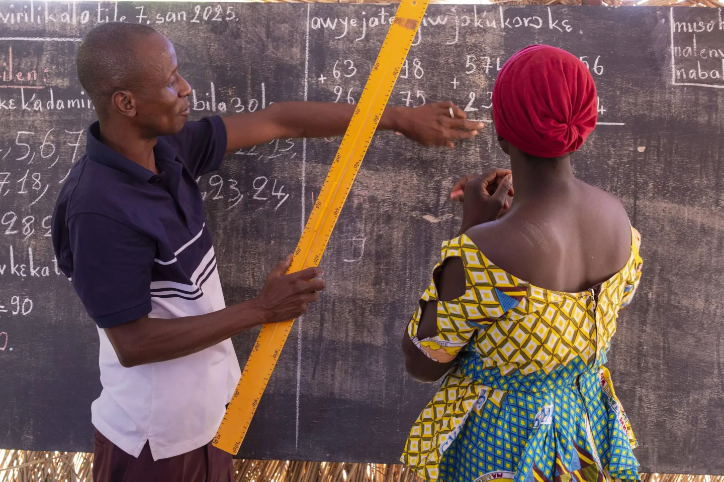 A man teaches a woman in a classroom in Mali