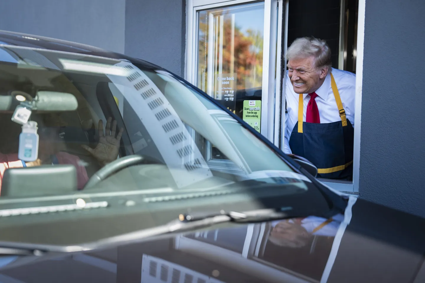 Donald Trump smiles through the pick-up window at someone excited in their car.