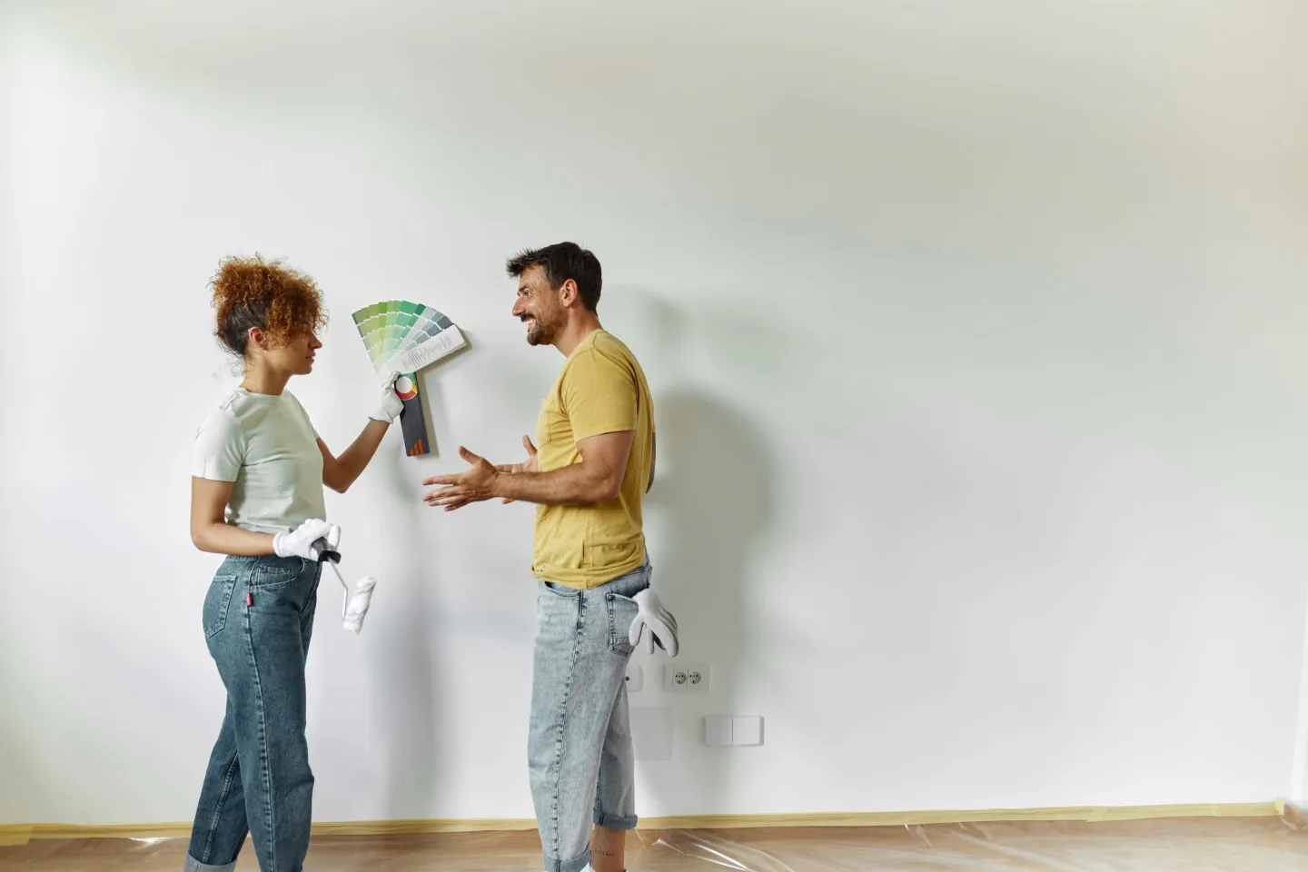Young happy couple talking while choosing colors for the wall while renovating their apartment. Copy space.