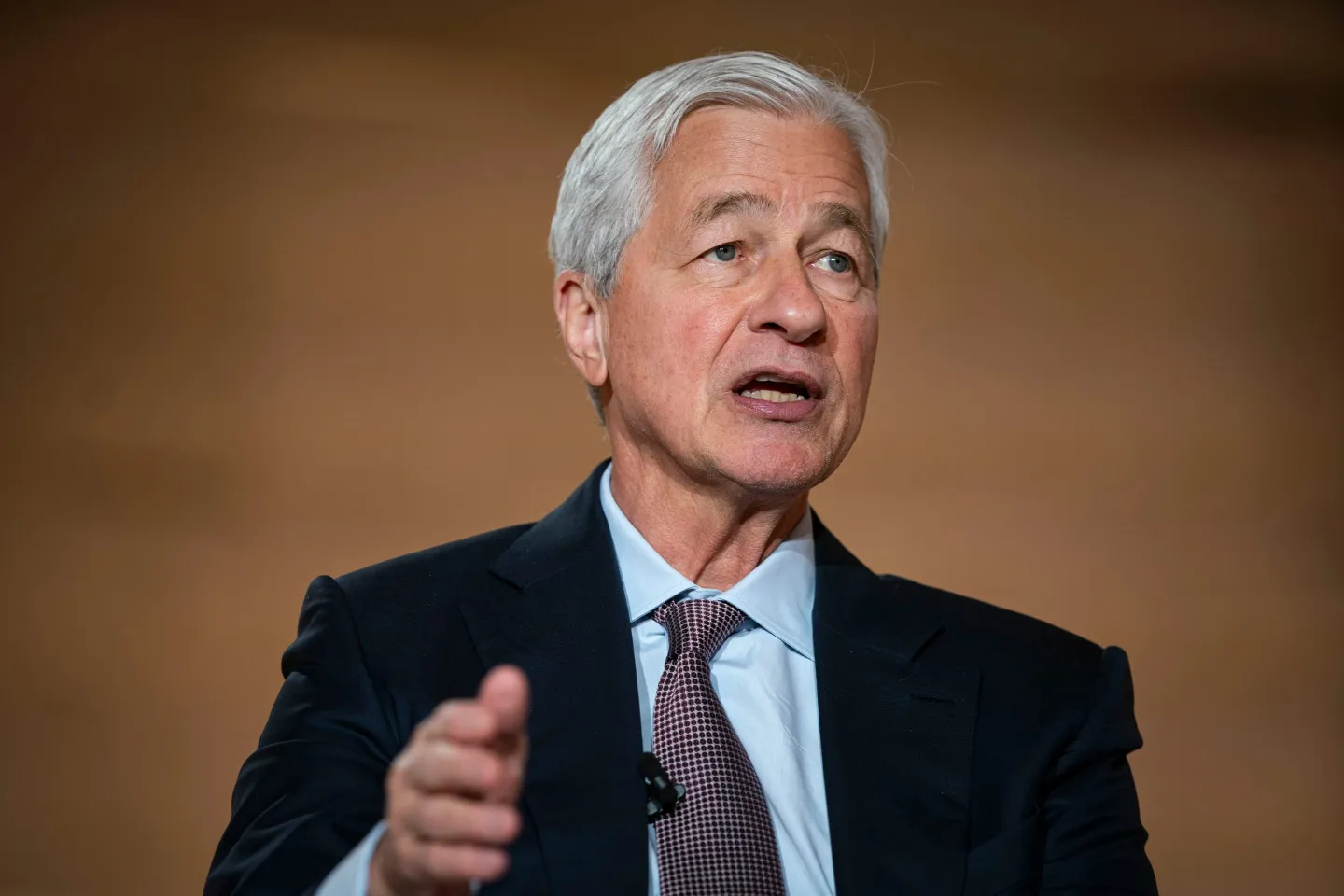 Jamie Dimon lifts his right hand as he speaks.
