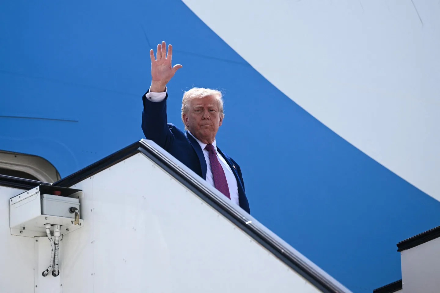 President Donald Trump waves goodbye aboard Air Force One